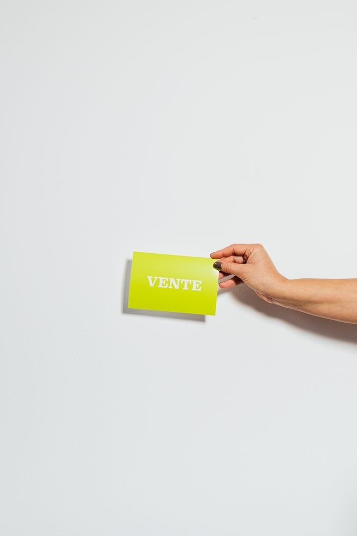 A hand holding a green sale card with copy space on a white background.